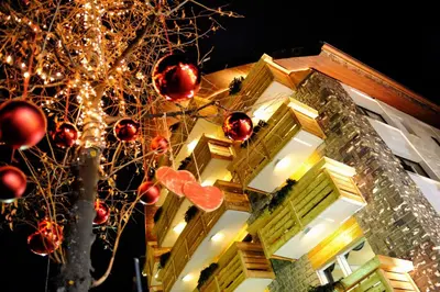 a christmas tree in front of a building with christmas decorations at Sport Hotel S. Vigilio in Moena