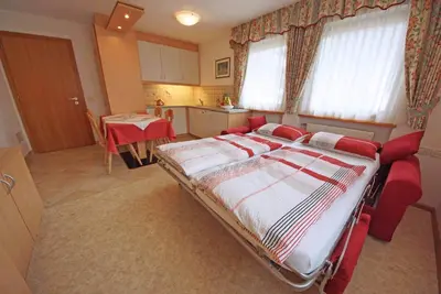 a bedroom with a large bed and a chair at Residence Araldina in San Cassiano