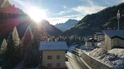 a snow covered mountain with the sun in the sky at Digonera Historic Hotel B&B in Rocca Pietore