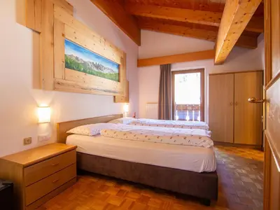 a bedroom with two beds and a table and a window at Apartment Garni Eden by Interhome in Soraga
