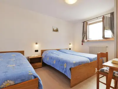 a bedroom with a blue bed and a wooden cabinet at Apartment Bernard-3 by Interhome in Campestrin