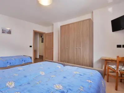 a bedroom with a blue bed and a desk at Apartment Bernard-3 by Interhome in Campestrin
