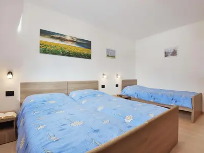 a bedroom with a bed with a blue comforter at Apartment Bernard-3 by Interhome in Campestrin