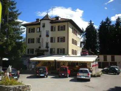 a large building with cars parked in a parking lot at Hotel Roen Ruffrè-Mendola in Mendola