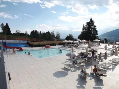 a large swimming pool with people sitting around it at Hotel Roen Ruffrè-Mendola in Mendola