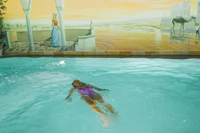 a woman is swimming in a swimming pool at Hotel Alba Wellness & Spa in Canazei
