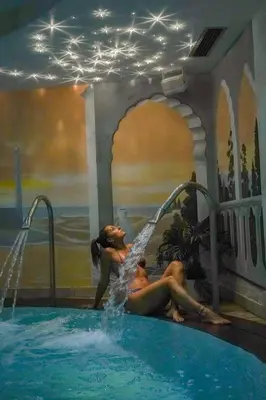 two women laying in a swimming pool in a swimming pool at Hotel Alba Wellness & Spa in Canazei