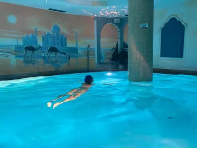 a person swimming in a swimming pool in a building at Hotel Alba Wellness & Spa in Canazei