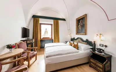 a bedroom with a bed and a table and a chair at Hotel Cavallino D'Oro Bed&Breakfast in Castelrotto
