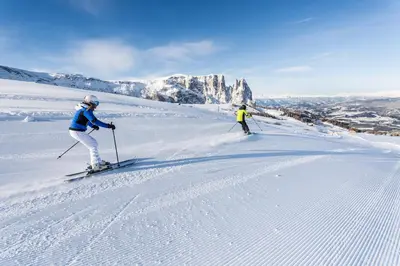 two people are skiing down a snow covered slope at Hotel Cavallino D'Oro Bed&Breakfast in Castelrotto