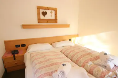 a bedroom with two beds with towels on them at Hotel Rosalpina in Soraga