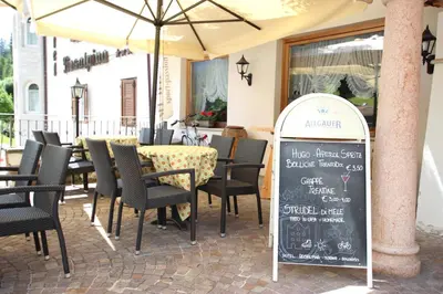 a restaurant with a chalkboard sign in front of a tables and chairs at Hotel Rosalpina in Soraga