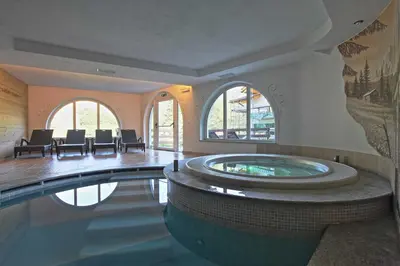 a large swimming pool with a hot tub in a building at Hotel Fanes Suite & Spa in Moena