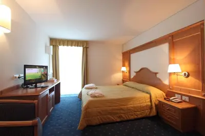 a hotel room with a bed and a flat screen tv at Hotel Fanes Suite & Spa in Moena