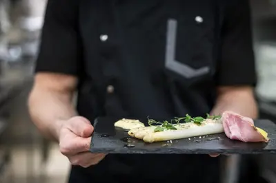 a chef holding a tray with food on it at SPA & Relax Hotel Erika in Tirolo