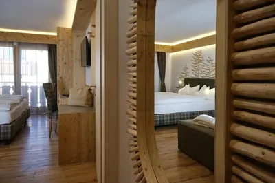 a room with a bedroom with a bed and a mirror at Cimon Dolomites Hotel in Predazzo