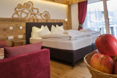 a hotel room with a bed and a basket of apples at Cimon Dolomites Hotel in Predazzo