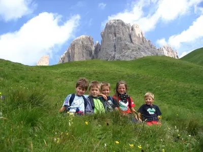 a group of children sitting on a grassy hill at Cimon Dolomites Hotel in Predazzo