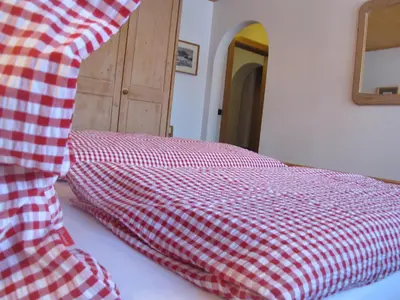 a red and white checkered blanket on a bed at Villa Ula Verda- Apartments Marianna in Santa Cristina in Val Gardena