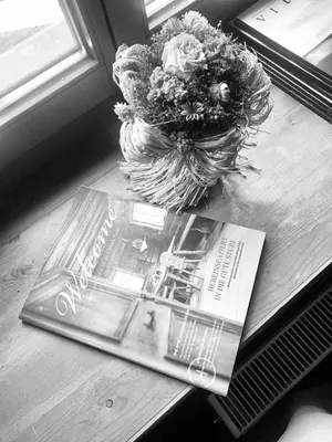 a magazine and a bouquet of flowers on a table at Chaletapartement Ambiente Villa Mozart mit Sauna in Chienes