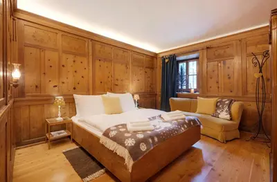 a bedroom with a large bed and a couch at Chaletapartement Ambiente Villa Mozart mit Sauna in Chienes
