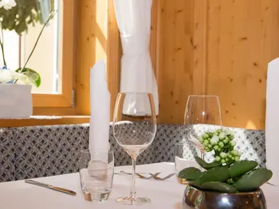 a table with two wine glasses and a candle at Hotel Blitzburg in Brunico