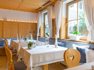 a restaurant with tables and chairs and windows at Hotel Blitzburg in Brunico
