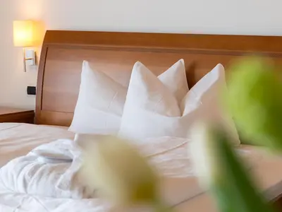 a bed with white pillows and a wooden headboard at Hotel Blitzburg in Brunico