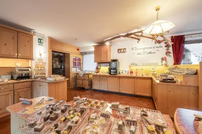 a large kitchen with wooden cabinets and a table with birds on it at Villa Adria B&B in Canazei