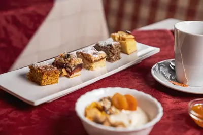 a plate of desserts on a table with a cup of coffee at Villa Adria B&B in Canazei
