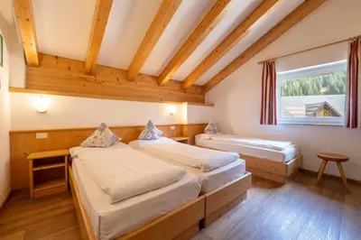 two beds in a room with a window at Villa Adria B&B in Canazei