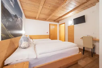 a bedroom with two beds and a desk at Villa Adria B&B in Canazei