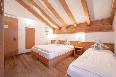 two beds in a room with wooden ceilings at Villa Adria B&B in Canazei