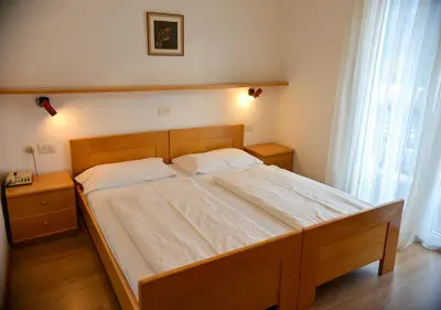 a bedroom with a large bed with white sheets at Hotel Regina Delle Dolomiti in Panchia