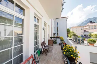 a balcony with chairs and flowers on a white house at Life Apartment & City Bike in Bolzano