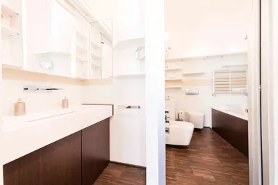 a bathroom with white counters and a toilet and a sink at Life Apartment & City Bike in Bolzano