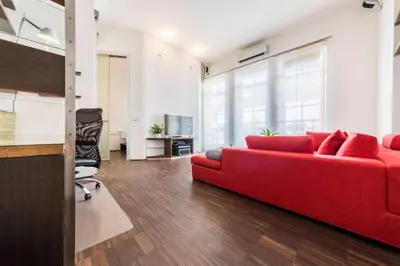 a living room with a red couch and a chair at Life Apartment & City Bike in Bolzano