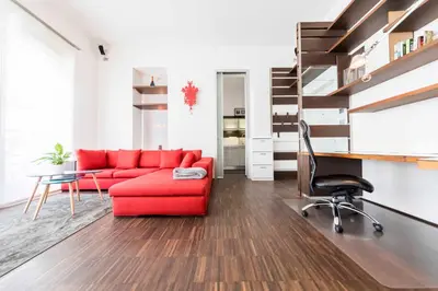 a living room with a red couch and a desk at Life Apartment & City Bike in Bolzano