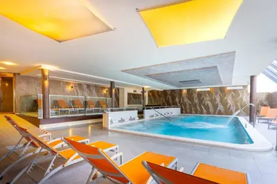 a large swimming pool in a room with chairs at Hotel Crepei in Pozza di Fassa