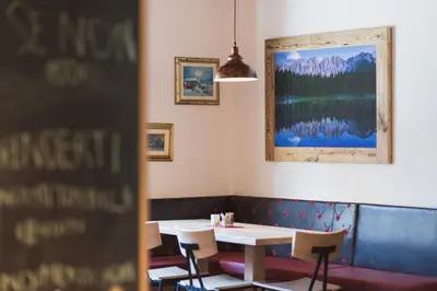 a table and chairs in a restaurant with a picture on the wall at Hotel Crepei in Pozza di Fassa