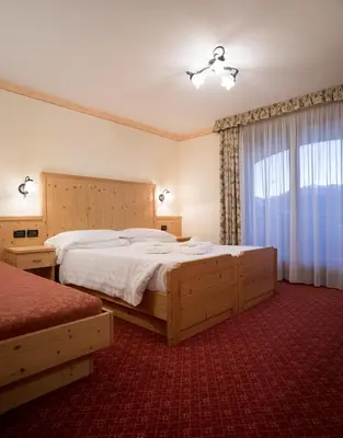 a bedroom with a large bed and a window at Hotel Crepei in Pozza di Fassa