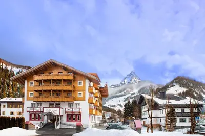 a ski lodge with a mountain in the background at Hotel Crepei in Pozza di Fassa