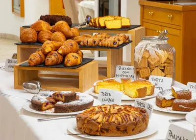 a table with different types of bread and pastries at Hotel Crepei in Pozza di Fassa