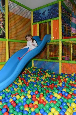 a boy sliding down a slide in a ball pit at Resort Dolce Casa - Family & Spa Hotel in Moena