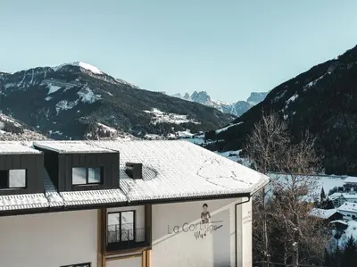 a house with a snowy roof with mountains in the background at La Cort My Dollhouse - Adults Only in Ortisei