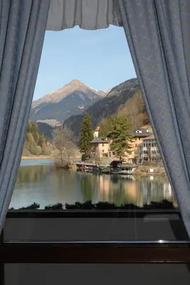 a window with a view of a lake and mountains at Sporthotel Europa Sul Lago in Alleghe