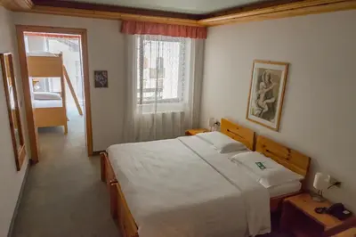 a bedroom with a large white bed and a window at Sporthotel Europa Sul Lago in Alleghe