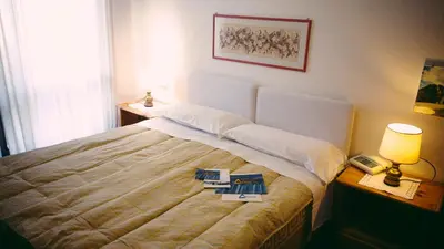 a bedroom with a bed with two lamps and a phone at Sporthotel Europa Sul Lago in Alleghe