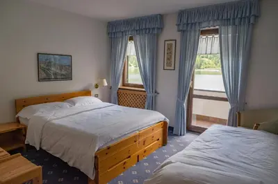 a hotel room with two beds and a window at Sporthotel Europa Sul Lago in Alleghe