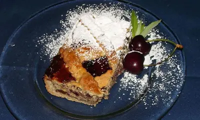 a piece of cake on a blue plate with a cherry at Park Hotel Miramonti in San Martino di Castrozza